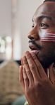 Watching tv, soccer and black man in home, nervous and frustrated for competition, anxiety and flag. Football, fan and person on sofa, match results and sports game with tournament, reaction or upset