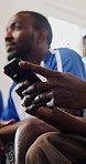 Hands, phone and friends on sofa for soccer game, watching tv or texting with streaming service. Men, group and smartphone with scroll, typing or notification on mobile app with football fans at home