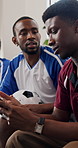 Men, phone and friends on sofa for soccer game, watching tv or distracted with texting in home. Group, stop typing and smartphone with talk, bored or chat on mobile app with football fans at house