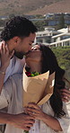 Couple, surprise and kiss with flowers outdoor for love, romance and anniversary gift on vacation. Wow, man and woman with bouquet at beach, hug and happiness with roses for present on holiday date