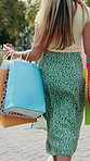 Hands, woman and walking with shopping bags in city for fashion discount, clearance sale and special. Back, shopper and designer gifts in urban town for boutique promotion, retail deal and purchase