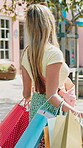Outdoor, woman and walking with bags, shopping spree and searching for clothes on discount and back. City, customer and person with presents on sale, travel and luxury purchase on summer holiday