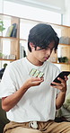 Phone, medicine and man in home for research, healthcare information or reading label for dose. Mobile, drugs and Asian person in house for medical prescription, benefits or side effects of pills