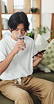 Man, water and sofa with phone for nutrition, mineral benefits or telehealth app in home. Male person, user or research with mineral liquid on mobile smartphone for healthcare or vitamins in house