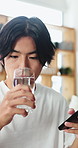 Man, drinking and water with phone for nutrition, mineral benefits or telehealth app in home. Male person, user or research with aqua liquid on mobile smartphone for healthcare or vitamins in house