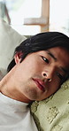 Thinking, Asian man and relax on couch at house with vision, loneliness and nostalgia memory. Bored, male person and overthinking with self reflection, remember decision and burnout of mental health