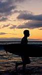Surfer, walking and man with silhouette, sunset and ocean for vacation, weekend activity and practice. Beach, surfboard or person with summer holiday, evening and hobby for health benefits or fitness