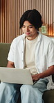 Happy, man and typing on laptop on sofa for university portal, study registration and feedback. Asian person, student and smile with tech in home for college enrollment, approval email and admission