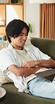 Streaming, laugh or Asian man in house with laptop, movie binging or funny video on online site. Happy, digital or person on sofa with tech, comedy show or series subscription on entertainment app.