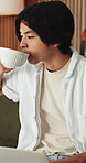 Coffee, remote work and man with laptop on sofa in home for freelance, planning or idea. Computer, drink and startup research with Asian person, entrepreneur and tech for small business in house