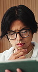 Asian man, tablet and relax in lounge with application for newsletter, notification or article at house. Person, tech and glasses for post, serious and perspective for headlines with story in home