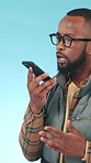 Phone call, hiker and black man on speaker in studio, trekking adventure and talk for travel holiday. Voice note, lost or person with mobile for emergency service contact, vacation or blue background