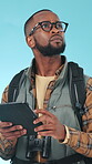 Hiking, backpack and black man in studio with tablet, search location and direction for tourist journey. Person, trekking and scroll with tech, digital map and guide for adventure on blue background.