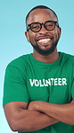 Face, volunteer and black man in studio with arms crossed, smile and social responsibility for NGO. Confident, person and charity worker with pride, non profit service and happy on blue background.