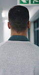 Man, walk and night at office in corridor with back, overtime and career at insurance company. Person, broker or advisor in hallway for deadline, job and break by window at risk management agency
