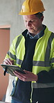 Construction, planning and man on tablet in building for design, research and online blueprints. Contractor, architecture and person on digital tech for renovation, maintenance or engineering project