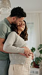 Couple, hug and happy for kiss in home with holding hands, care and connection in nursery. People, man and pregnant woman with embrace, touch belly or support for prenatal development at apartment
