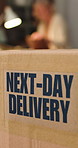 Logistics, box or shipping label in office, package distribution or rush order for next day delivery. Freight, supply chain and parcel with express sticker to streamline transport, startup and people