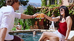 Holiday, couple and cheers with drinks at swimming pool for summer celebration, bonding and relax. Villa, people and happy with alcohol toast at poolside for vacation trip, weekend break and unwind