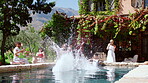 Friends, man and jump in pool with summer holiday, party outdoor or bonding together in home backyard. People, fun vacation and person leap with splash, swimming or social gathering for weekend break