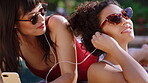 Music, phone and women outdoor at pool together for audio, song or sound streaming in summer. Earphones, relax and sharing with friends sunbathing on holiday for travel break, trip or vacation