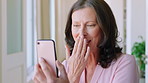 Woman, phone and video call in home with surprise, conversation and smile for unexpected good news. Mature, person and wave in house with tech, contact and virtual conference for shocking discussion.