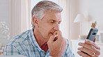 Elderly, man and thinking with phone in home for online research, decision or tough choice. Senior, male person or scrolling with mobile smartphone for web browsing, selection or pick on app in house