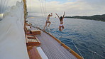 Friends, vacation and jump off boat in sea with travel adventure, swimming and fun trip for tourism. People, summer holiday and leap from yacht with nature exploration, bonding and sailing on ocean.