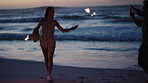 Sunset, picture and couple with sparklers on beach for celebration, new years eve and summer vacation. Dating, love and man with woman with photo for holiday, bonding and memory together by ocean