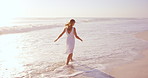 Woman, walk and summer holiday on beach with waves, kick water and enjoy getaway for weekend break. Back, female person and splash outdoor in ocean with peace, wellness and travel for vacation trip.