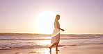 Woman, sunset and walking on the beach for travel, calm and vacation wellness outdoor. Sky, space and female person on ocean shore for peace, fresh air and break on getaway trip for self care