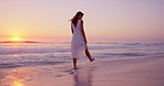 Travel, walk or woman at beach with thinking, sunset or peaceful mindset on seaside vacation. Stroll, wave splash or tourist at ocean with getaway, calm perspective or summer evening on holiday break
