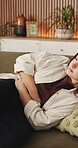 Woman, sick and stomach ache on couch with menstruation cramps, discomfort or indigestion problem. Female person, abdominal pain or inflammation in home with period cycle, endometriosis or gastritis.