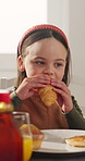 Breakfast, kid and eating croissant for nutrition, wellness and chat with child in dining room. Morning, hungry girl and bite food for diet, growth and meal for development with health in home