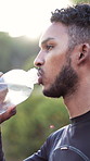 Athlete, fitness and man with drinking water outdoor for exercise hydration, cardio break and bokeh. Health, runner and beverage in nature for workout thirst, nutrition and electrolytes for wellness