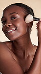Face, woman and makeup application with brush, foundation coverage and product for beauty routine. Black person, smile and cosmetic tools for self care, glowing skin or grooming on studio background.