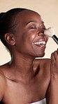 Woman, laugh and makeup application with brush, foundation and facial product for beauty routine. Happy, black person and cosmetic tools for self care, glowing skin and grooming on studio background.