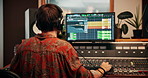 Production, music and back of producer with headphones in studio working on album or song with computer. DJ, equipment and male sound technician with technology for mixing audio in recording booth.