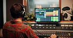 Production, music and back of engineer with headphones in studio working on album or song with computer. DJ, equipment and male sound producer with technology for mixing audio in recording booth.
