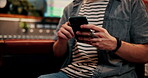 Producer, man and hands in recording studio with phone, scroll website and trends for inspiration. Music artist, person and typing with tech for research, creativity and download app for song ideas.