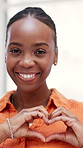 Face, heart hands and black woman in home, smile and icon for kindness, care and support. Apartment, gesture and African person in living room, happiness and symbol for love, emoji and flirting