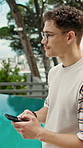 Man, phone and vacation with pool for travel, weekend and typing with break. Hotel, summer holiday and person with tech for influencer, social media and connection with app and luxury resort review