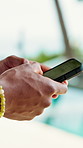 Hands, person and typing with phone at resort for travel, social media and browsing website. Tourist, scroll and mobile for communication, online itinerary and notification update on holiday at hotel