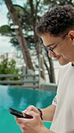 Man, phone and outdoor at resort with summer holiday, social media post and website for accommodation. Person, smile and scroll by swimming pool with tech, vacation and mobile app for booking hotel.