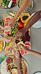 Hands, friends and cheers with champagne for brunch reunion, celebration and organic snacks. Above, people and toast drinks with fruit board, social gathering and bonding together for weekend break