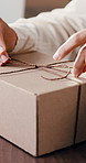 Hands, wrap and person with box in office for logistics, delivery or order package for courier. Service, ecommerce and female entrepreneur with strings for product in workshop for distribution.