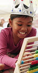 Learning, growth and girl in house with abacus, math practice or fun activity in literacy skills. Education, smile or child in home with crown, bead counting or number play for cognitive development.