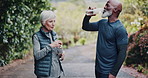 Drinking, water and old couple at park for fitness, hydration and running with partner for wellness. Outdoor, senior runner and interracial people with liquid in nature, cardio and workout routine