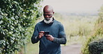 Senior, black man and fitness with phone in nature for workout app or monitoring performance. Active, elderly or African male person scrolling with mobile smartphone for exercise routine or schedule