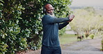 Stretching, outdoor and black man with fitness, wellness and headphones for audio, nature and workout. Runner, training or mature person with practice, warm up for health benefits and listen to radio